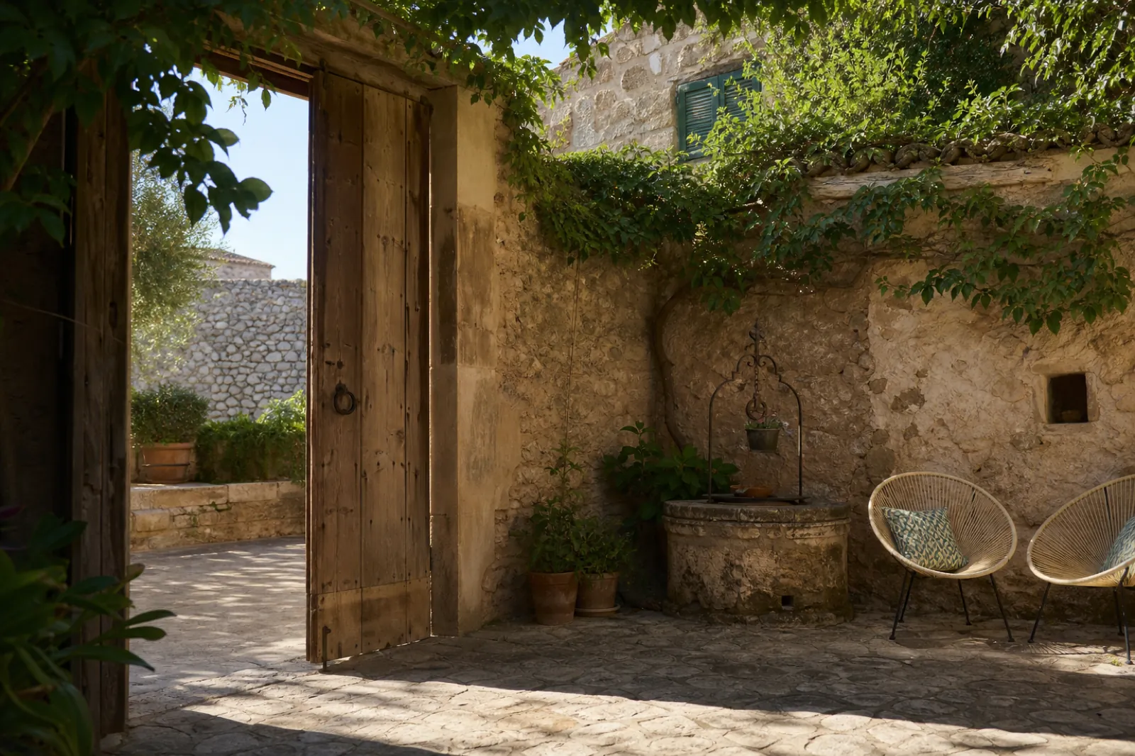 Patio eines Dorfhauses im Inselinneren mit altem Brunnen, Stein und Holztor
